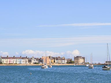 A harbor with sailboats on the water and colorful houses along the shore at Lluest in Beaumaris