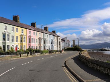 A row of pastel colored houses along a curved road by the waterfront at Lluest in Beaumaris