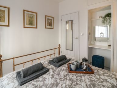 A bedroom with a brass bed frame towels on the bed and a tray with mugs and a coffee press at Primrose End in Jacobstow