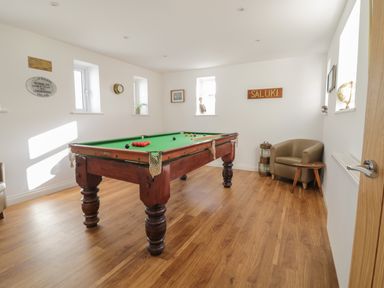 A room with a pool table wooden floor and armchair with small table at The Bull Inn in Deiniolen