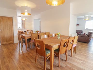 A dining room with wooden tables and chairs and hanging lights at The Bull Inn in Deiniolen