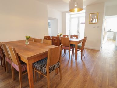A dining room with two wooden tables and chairs with patterned cushions at The Bull Inn in Deiniolen