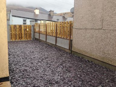An outdoor area with a gravel ground surface enclosed by wooden fences and a gate at The Bull Inn in Deiniolen