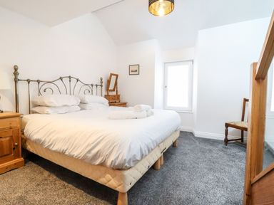 A bedroom with a double bed white bedding wooden furniture and a window at The Bull Inn in Deiniolen