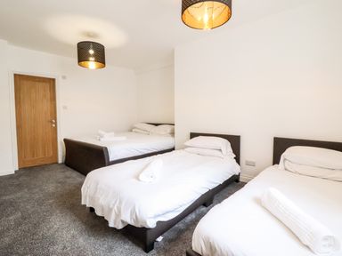 A bedroom with three beds and a wooden door at The Bull Inn in Deiniolen