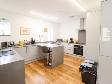 A kitchen with modern appliances counter stools and wooden flooring at The Bull Inn in Deiniolen