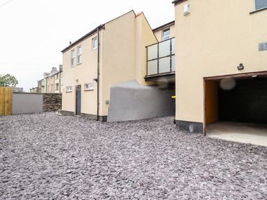 A gravel driveway and parking area with a garage and beige buildings at The Bull Inn in Deiniolen