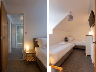A bedroom with two single beds a bedside table with a lamp a chest of drawers and a wall mounted tv at Rose Cottage in St Ives