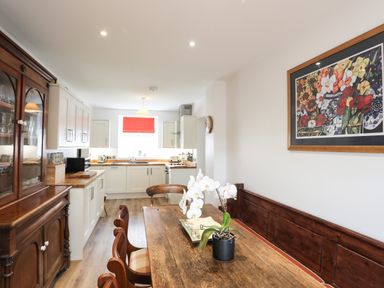 A kitchen with wooden dining table and chairs and white cabinets at Bryn Afon Farm in Llanrug