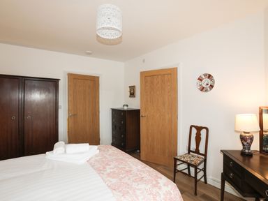 A bedroom with a bed folded towels dark wooden furniture a chair and two wooden doors at Bryn Afon Farm in Llanrug