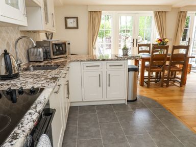 A kitchen with a marble countertop dining table and wooden chairs near glass doors at Garden Cottage in Garndolbenmaen near Tremadog