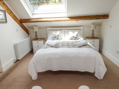 A bedroom with a double bed under a skylight with bedside tables and lamps at Garden Cottage in Garndolbenmaen near Tremadog