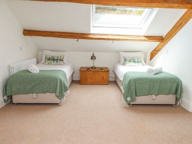 A bedroom with two single beds green blankets a wooden chest and a skylight window at Garden Cottage in Garndolbenmaen near Tremadog