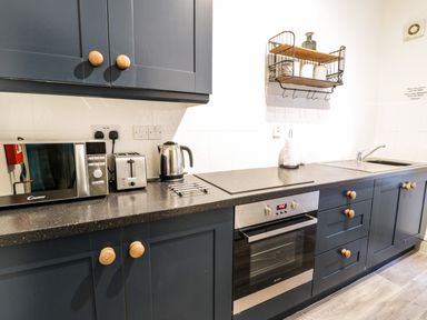 A kitchen counter with microwave toaster kettle oven sink and cabinets at Sapphire Suite in Barmouth