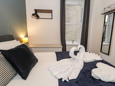 A bedroom with a made bed and towel swans on the bed at Sapphire Suite in Barmouth