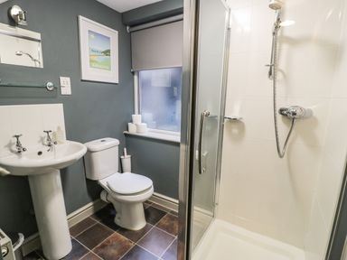 A bathroom with a shower cubicle toilet and sink at Sapphire Suite in Barmouth