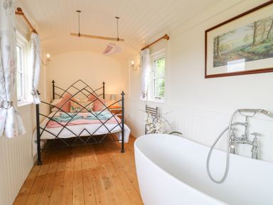 A bedroom with a metal bed and a freestanding bathtub at Shepherds Hut Colton near Rugeley Staffordshire