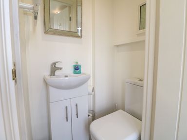 A small bathroom with a white sink and cabinet a mirror a toilet and hand soap at Shepherds Hut Colton near Rugeley Staffordshire