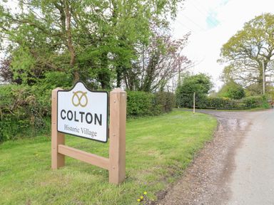 A road sign saying Colton Historic Village beside a country road with trees and grass at Shepherds Hut in Colton near Rugeley Staffordshire