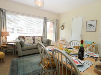 A dining area with a set table and a sitting area with a sofa and side tables at The Nook in Mundesley