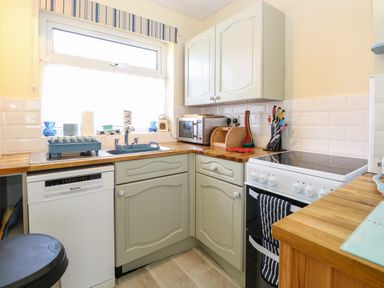 A kitchen with a sink dishwasher microwave stove and knife set at The Nook in Mundesley
