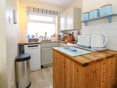 A kitchen with wooden countertops including a toaster kettle microwave and dishwasher at The Nook in Mundesley