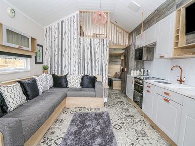 An open living room and kitchen area with a sectional sofa and patterned floor at Hares Rest in Nantmel near Rhayader