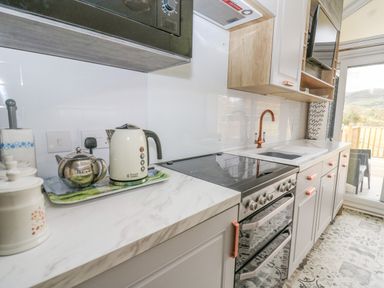A kitchen with a kettle teapot stovetop oven and sink at Hares Rest in Nantmel near Rhayader