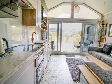 A kitchen and living area with sliding glass doors to a deck and hills at Hares Rest in Nantmel near Rhayader