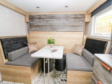 A dining area with a table and cushioned benches with a window at Hares Rest in Nantmel near Rhayader