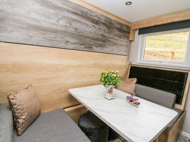 A dining area with a marble table a flower vase cushions and a window at Hares Rest in Nantmel near Rhayader