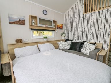 A bedroom with a bed and cushions on a sofa against a patterned wall at Hares Rest in Nantmel near Rhayader