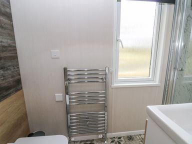 A bathroom with a window a chrome towel radiator a toilet and part of a sink at Hares Rest in Nantmel near Rhayader