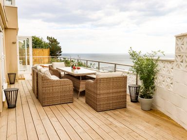 A balcony with rattan chairs and table overlooking the sea at Ocean View in Downderry