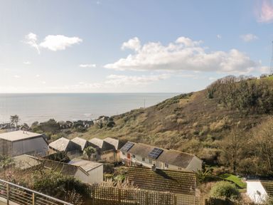 A coastal view with houses on a hillside and the sea in the background at Ocean View in Downderry