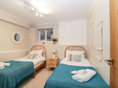 A bedroom with two single beds a nightstand and window at Ocean View in Downderry