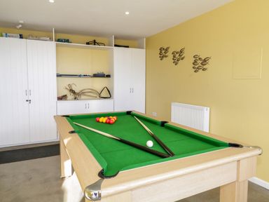 A game room with a pool table and white storage cabinets at Ocean View in Downderry