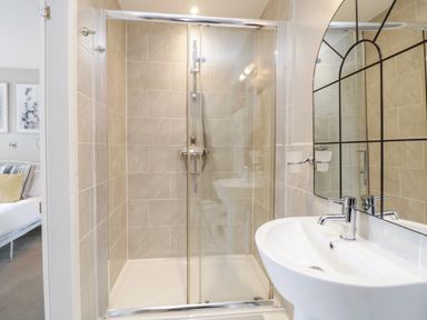 A bathroom with a tiled shower enclosure a white sink and a mirror at Ocean View in Downderry