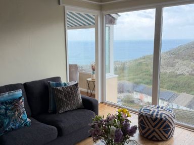 A living room with a sofa and a flower arrangement at Ocean View in Downderry