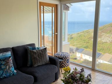 A living room with a sofa and flower arrangement at Ocean View in Downderry