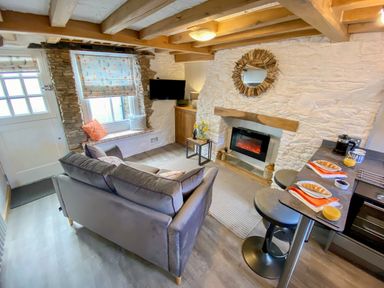 A living room with a sofa a window seat and a fireplace at Pilchard Cottage in Brixham