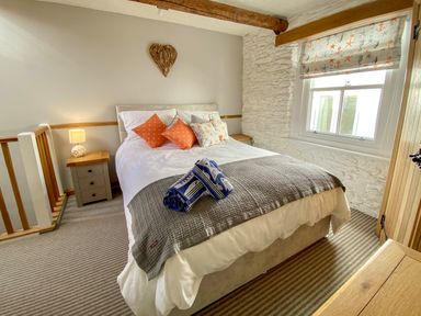 A bedroom with a bed pillows bedside tables and a window at Pilchard Cottage in Brixham