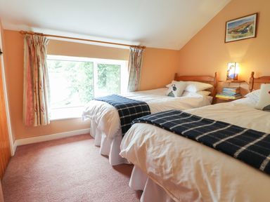 A bedroom with two single beds with white bedding and blue blankets near a window at Penllain in Newport Pembrokeshire