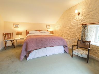 A bedroom with a bed bedside tables chairs and a window at Penllain in Newport Pembrokeshire