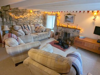 A living room with a sofa, armchair, and a television at Penllain in Newport, Pembrokeshire