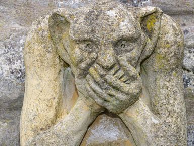 A stone statue of a creature covering its mouth with both hands