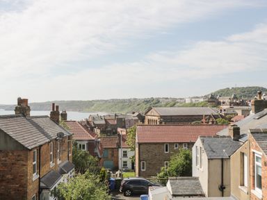 A view of rooftops with buildings hills and ocean in the background at Rydal Cottage in Scarborough