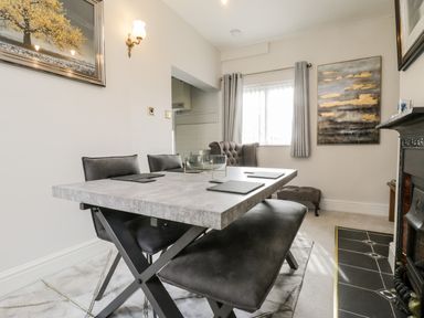 A dining room with a table and chairs near a window and fireplace at Rydal Cottage in Scarborough