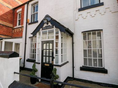 Black and white cottage entrance with glass door and windows named Rydal Cottage in Scarborough