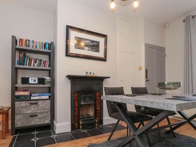 A dining room with a table and chairs a bookshelf and a fireplace at Rydal Cottage in Scarborough